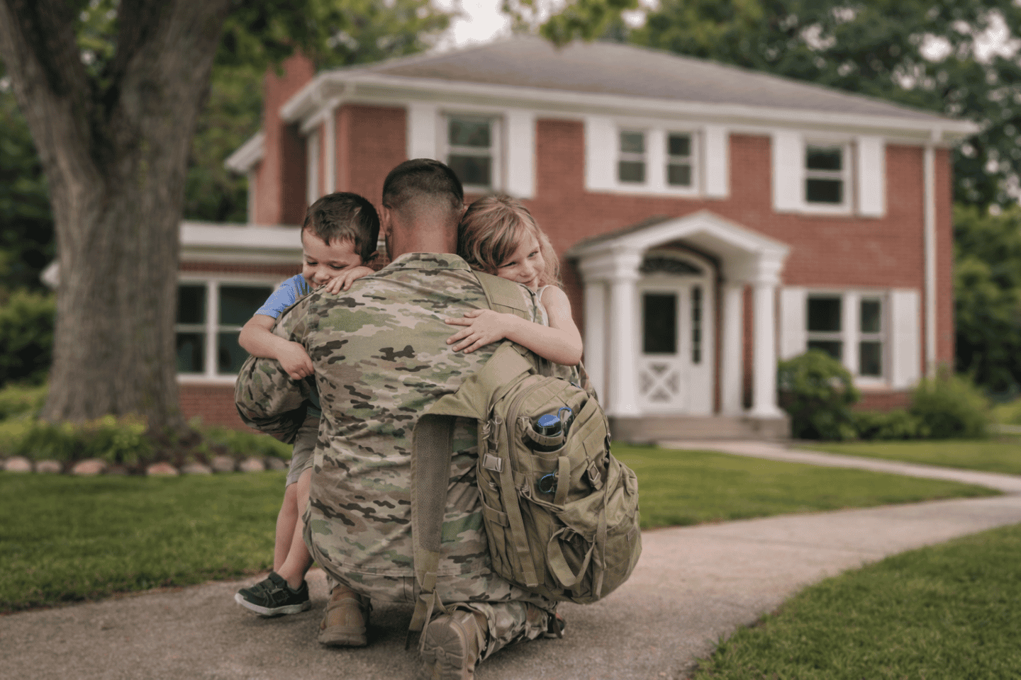 Rear view of a soldier in uniform embracing his children.