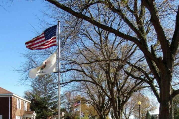 American flag waving in the wind against a backdrop of trees on VFW National Home’s campus.