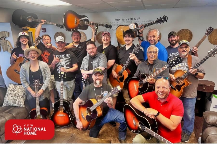 A group of people holding guitars during Military Appreciation Month at VFW National Home’s Guitars for Vets program.