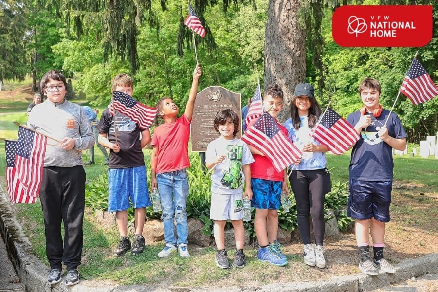 National Home residents holding American flags at Maple Hill Cemetery during Memorial Day.