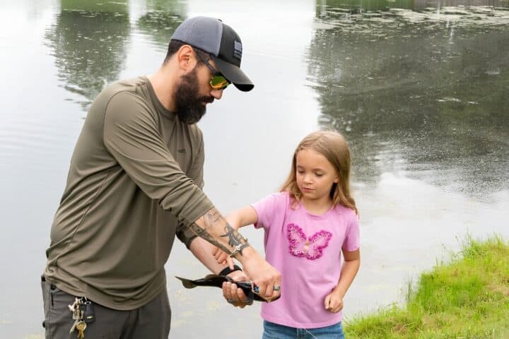Military father and daughter fishing together at a lake near VFW National Home's campus.