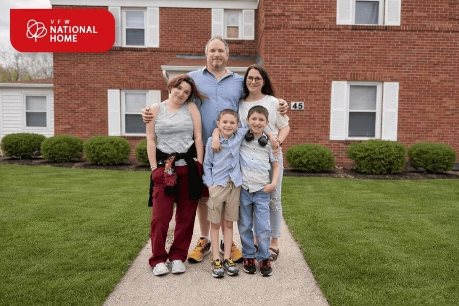 Military family standing outside housing provided by VFW National Home during Military Appreciation Month.